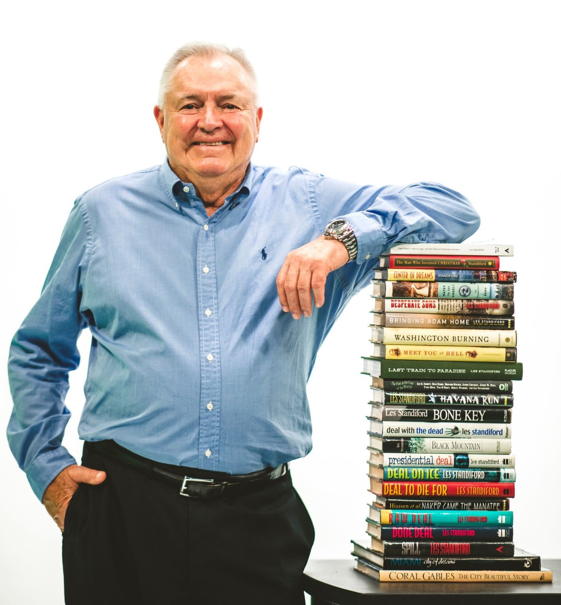 Les Standiford standing with stack of books